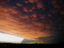 Orange Mammatus in the foreground, with two weaker thunderstorms developing below.